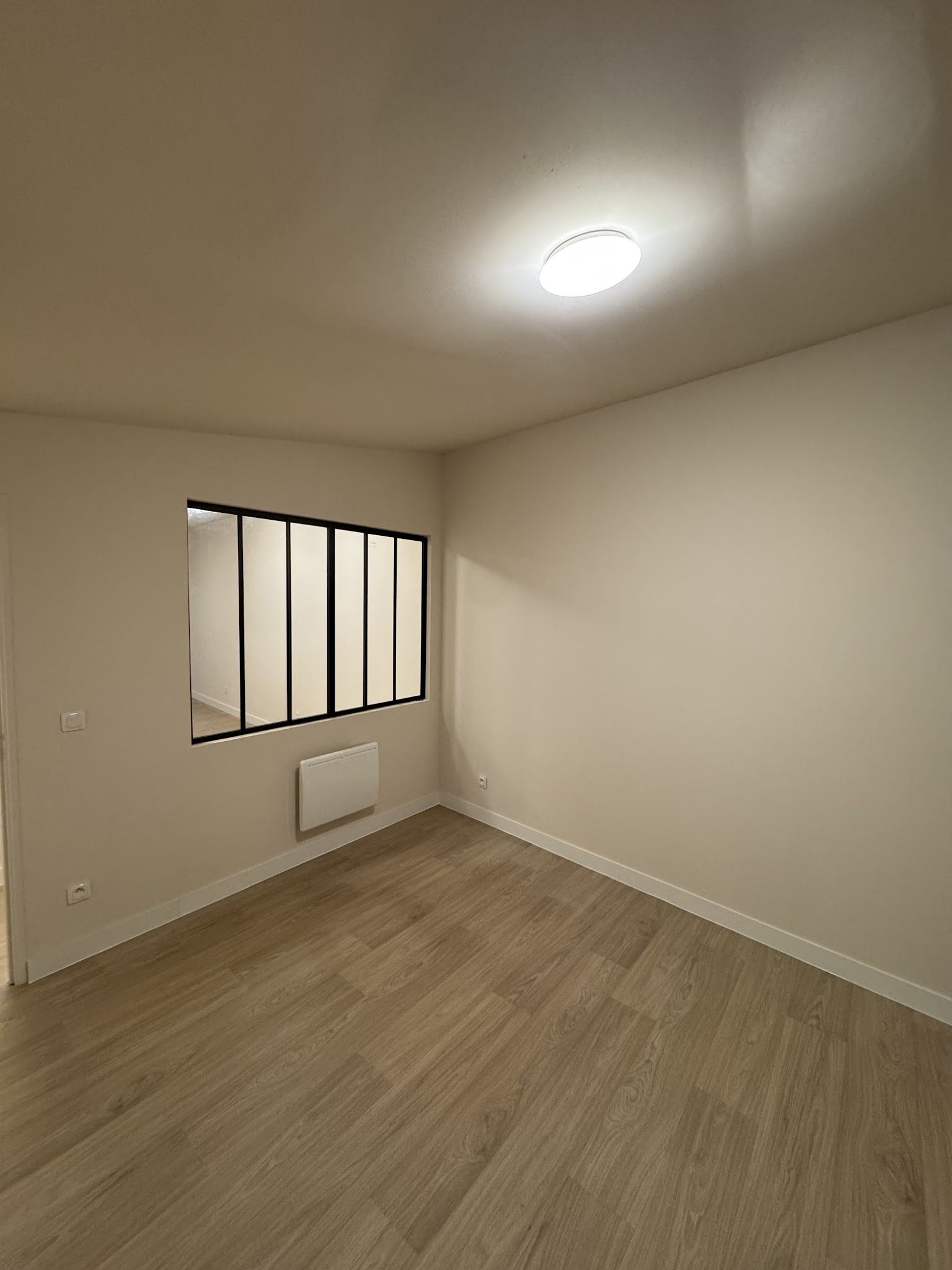 Pièce aux murs et plafond fraîchement repeints, verrière noire